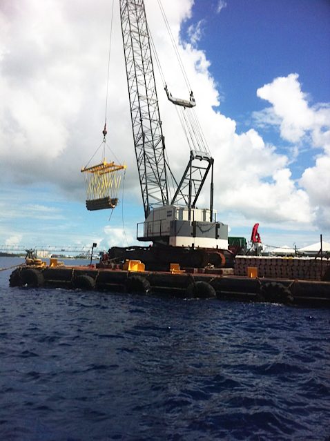 Crawler crane on a barge lifting a load
