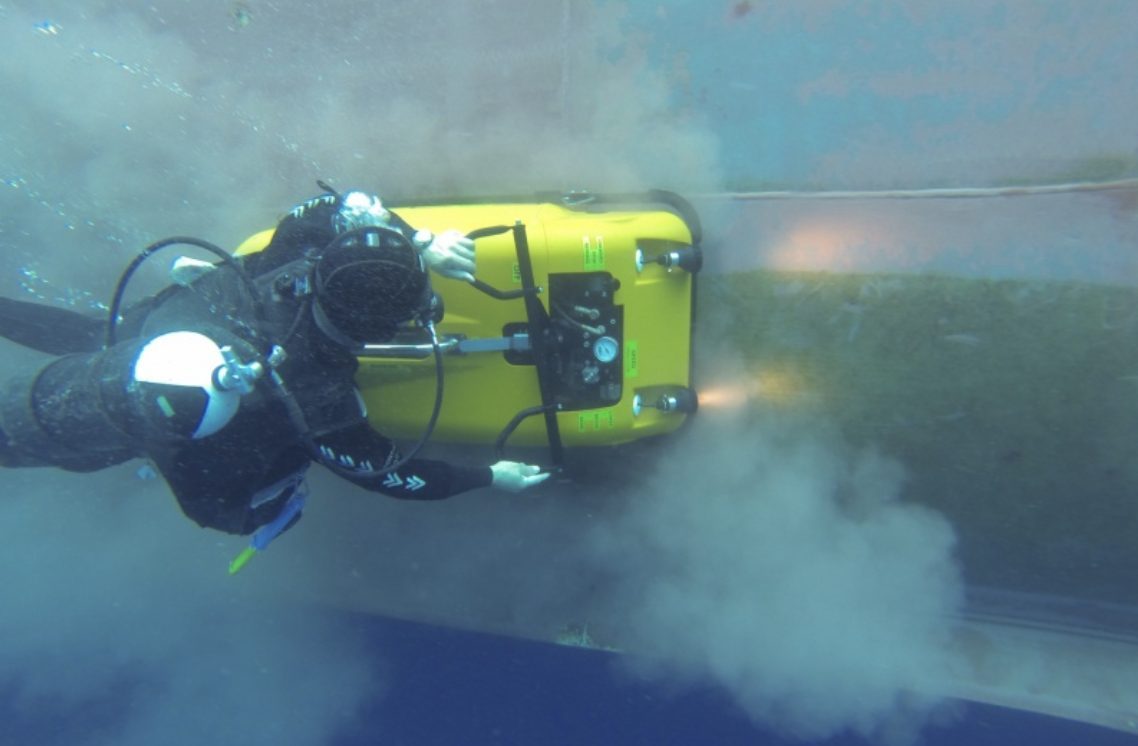 Diver operating a hull cleaning machine